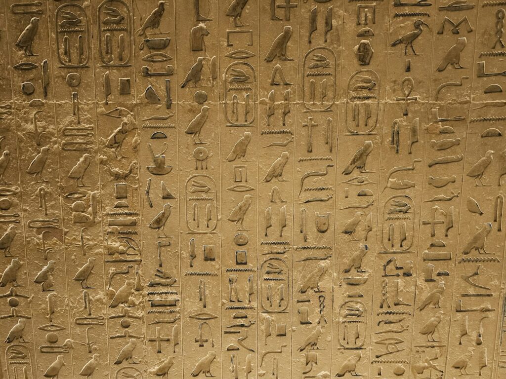 a wall with egyptian writing and birds on it